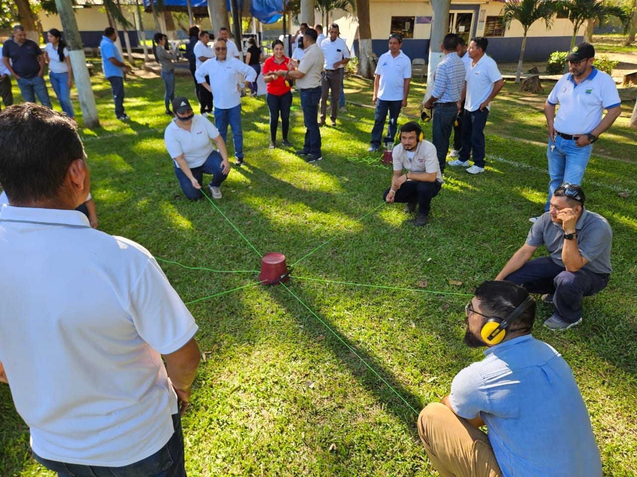 Equipo de participantes realizando una dinámica de trabajo en equipo al aire libre, conectados mediante cuerdas